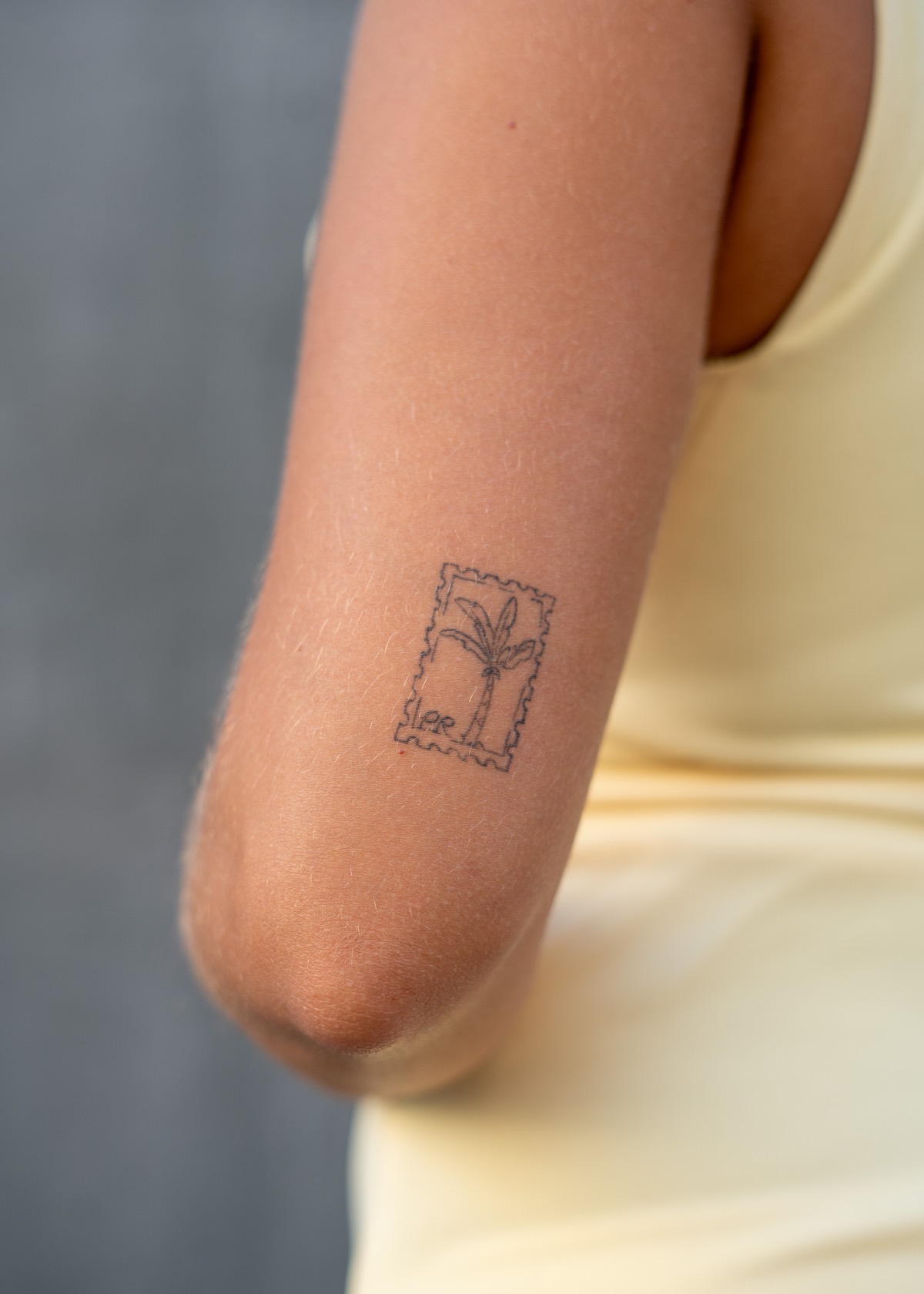 Tatuaje de un sello de correos de Puerto Rico con una palmera, en el brazo de Fiama